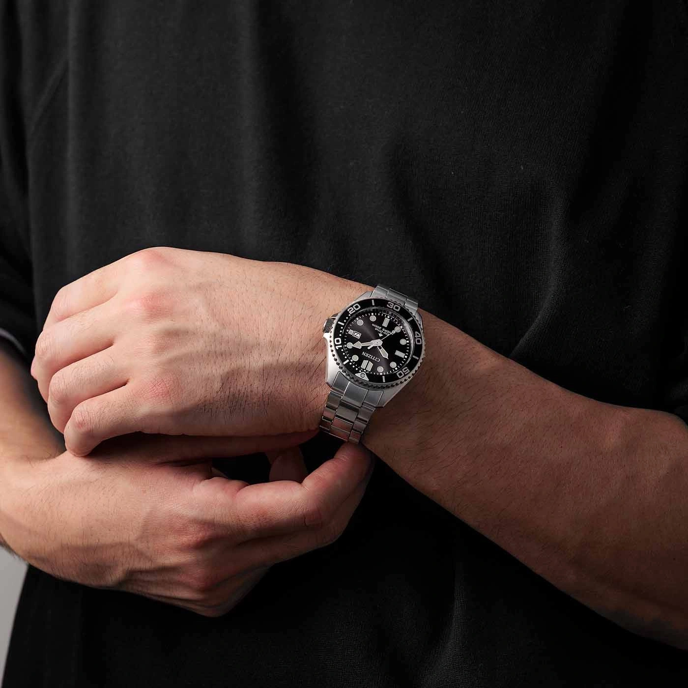 Mann trägt eine silberne Uhr mit schwarzem Zifferblatt am Handgelenk
