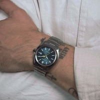 Ein Männerhandgelenk mit einer Citizen Eco-Drive Uhr und Tattoos.