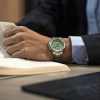 Ein Mann im Anzug liest ein Buch und trägt eine grüne Citizen-Uhr.