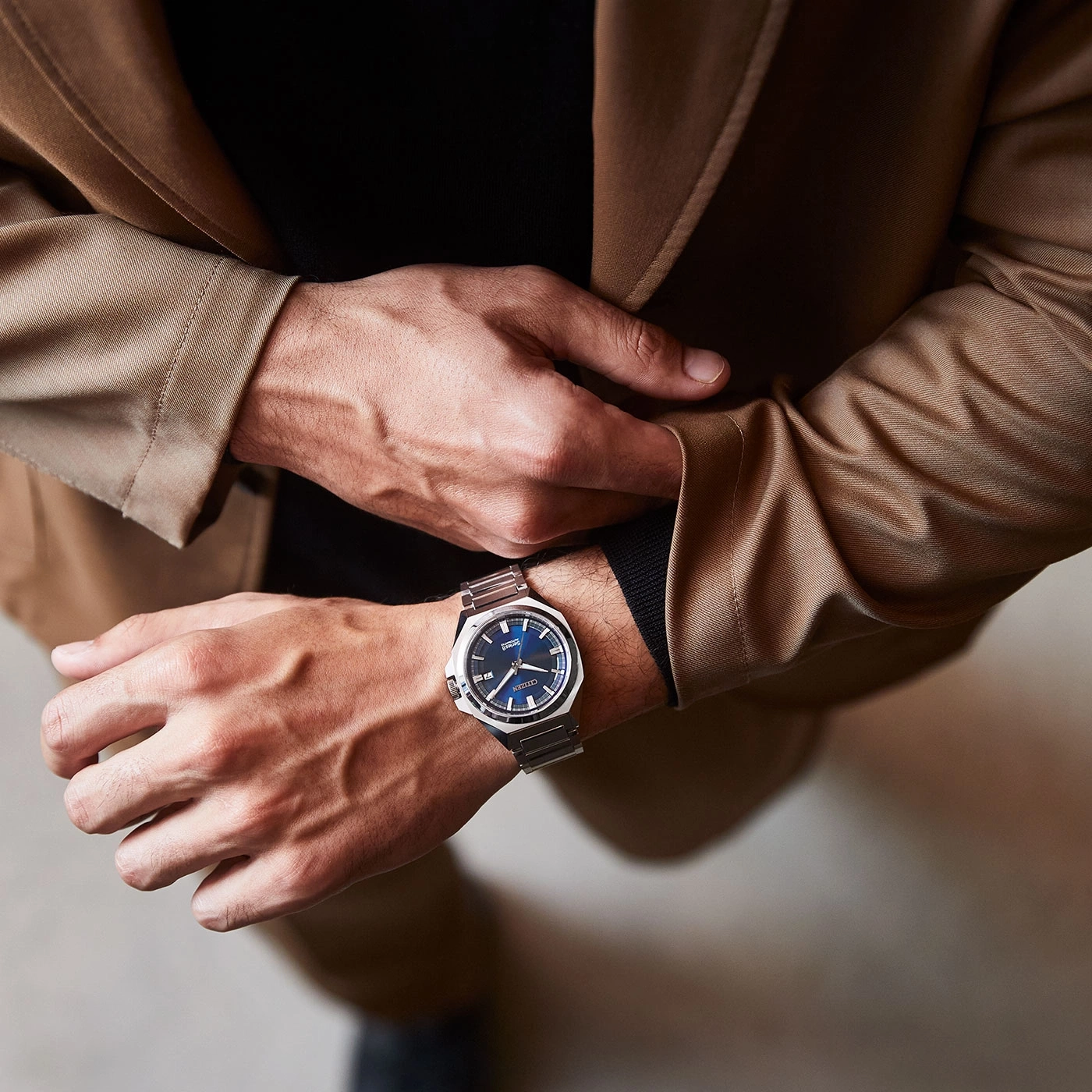 Mann mit Uhr, Anzugjacke und schwarzem Hemd, Nahaufnahme.