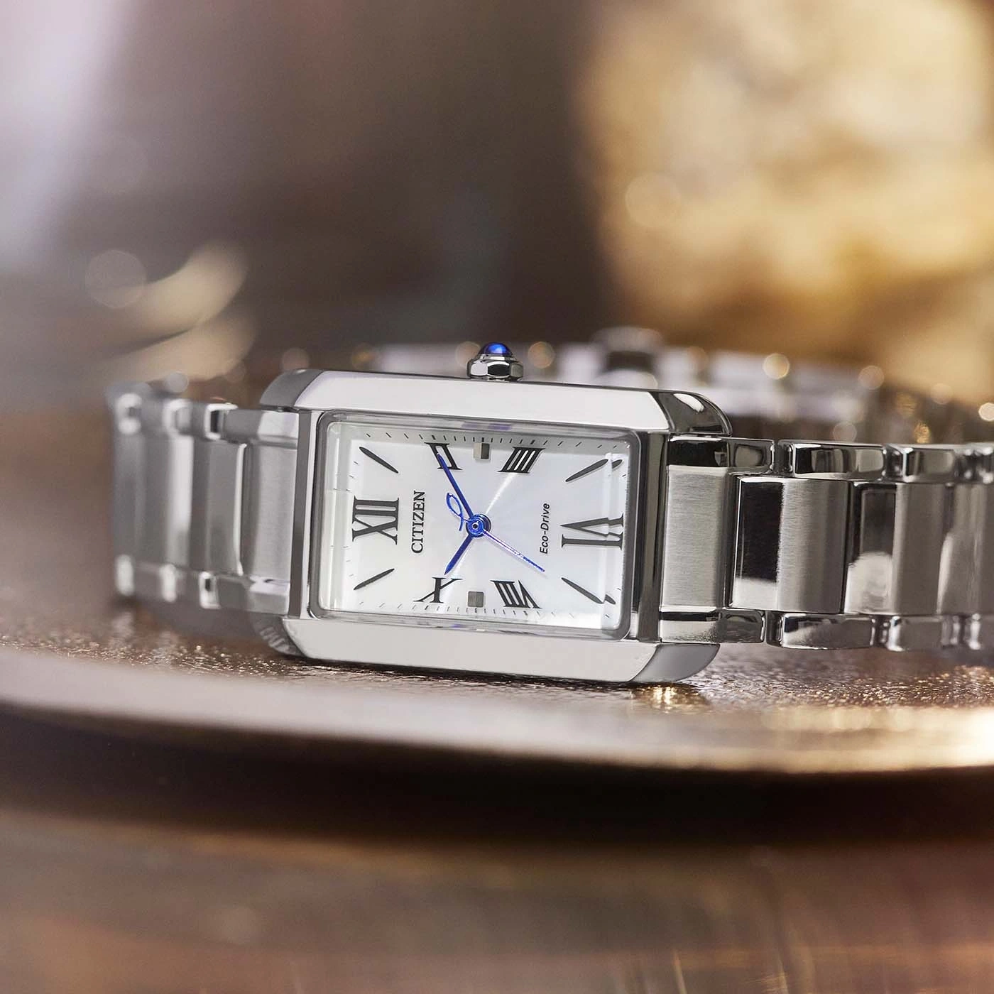 Citizen-Uhr mit weißem Zifferblatt und silbernem Armband auf reflektierender Oberfläche