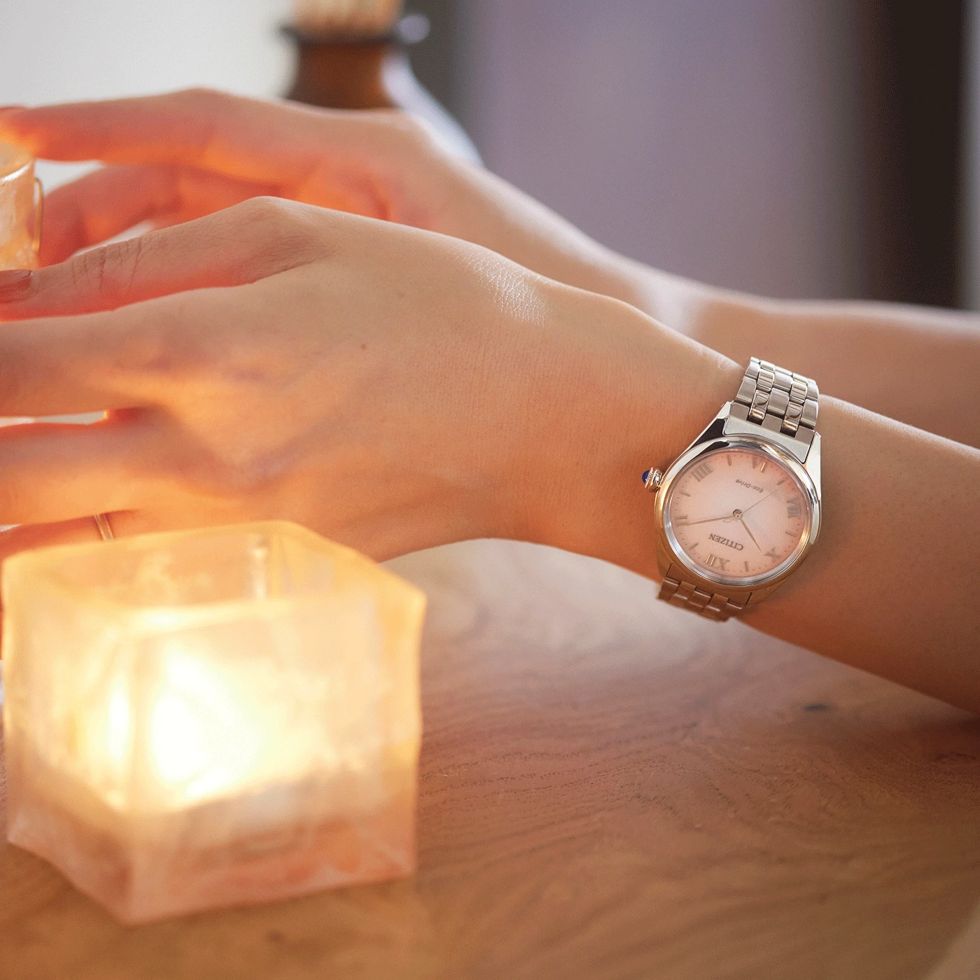 Handgelenk mit Uhr, Kerze und Holztisch. Romantische Beleuchtung.