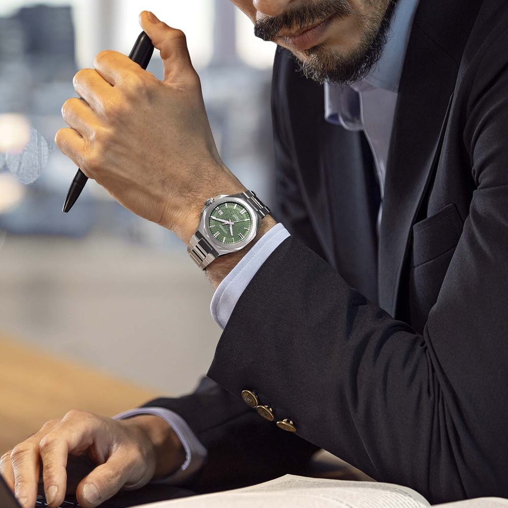 Mann im Anzug mit Uhr und Stift am Schreibtisch
