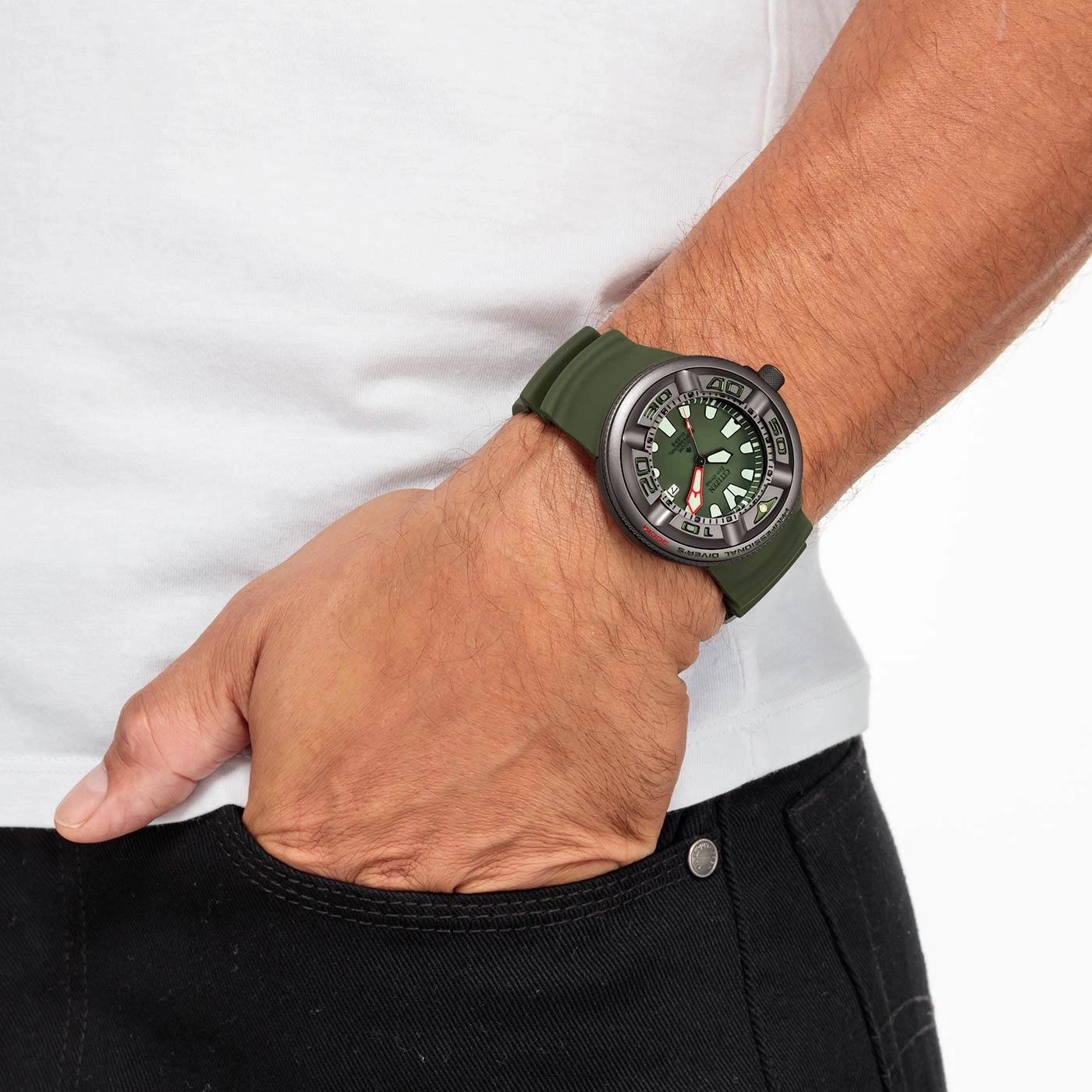Mann trägt grüne Uhr, Hand in der Tasche, weißes Hemd, schwarze Hose.