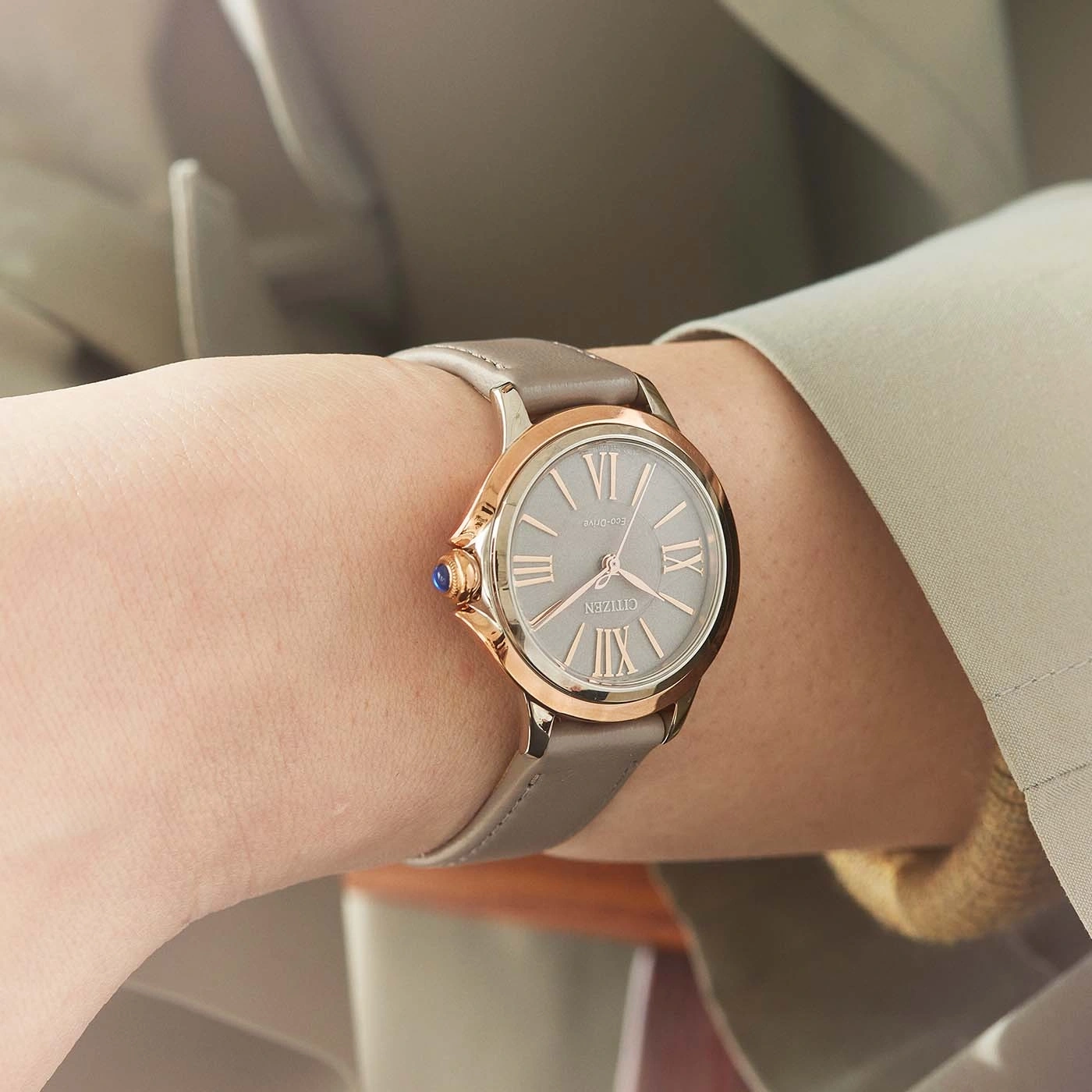 Nahaufnahme einer Citizen-Uhr am Handgelenk, mit grauem Armband und roségoldenen Akzenten.