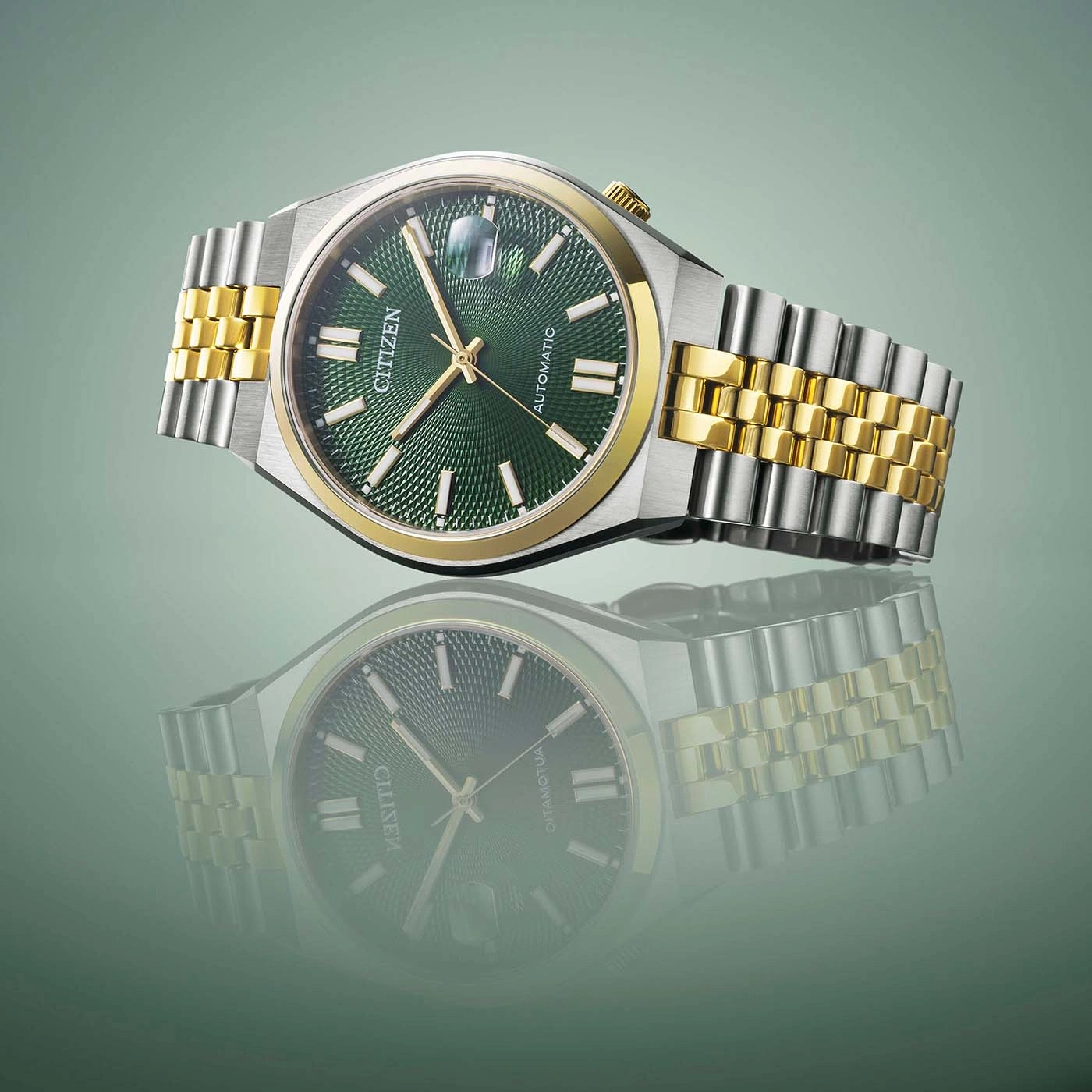 Citizen-Uhr mit grünem Zifferblatt und Gold- und Silberband, reflektiert.