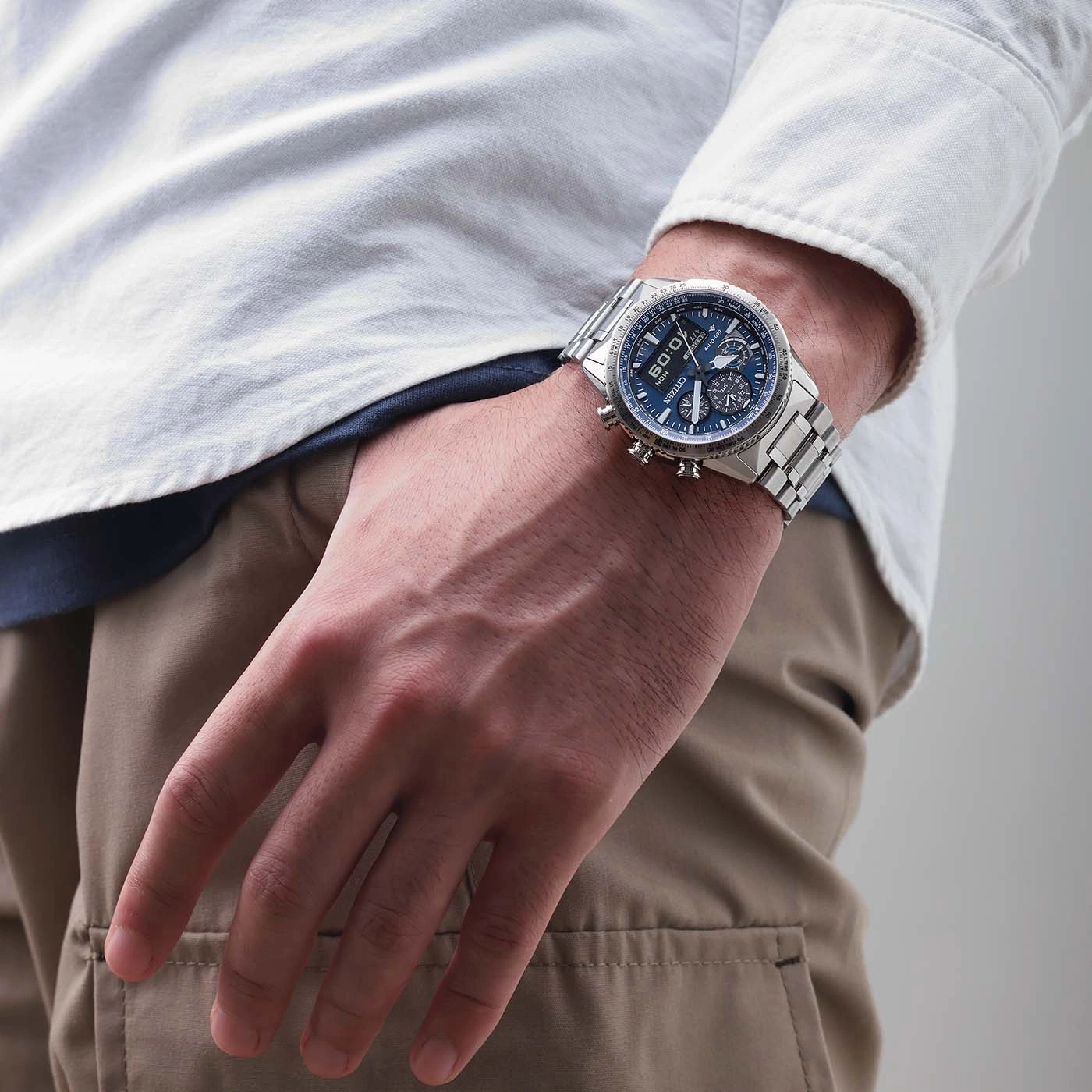 Mann trägt silberne Uhr mit blauem Zifferblatt und weißem Hemd.