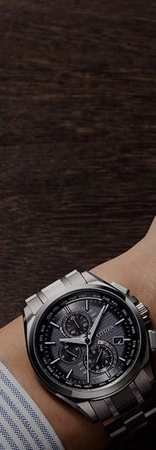 Nahaufnahme einer Citizen-Uhr am Handgelenk, mit dunklem Holz Hintergrund.