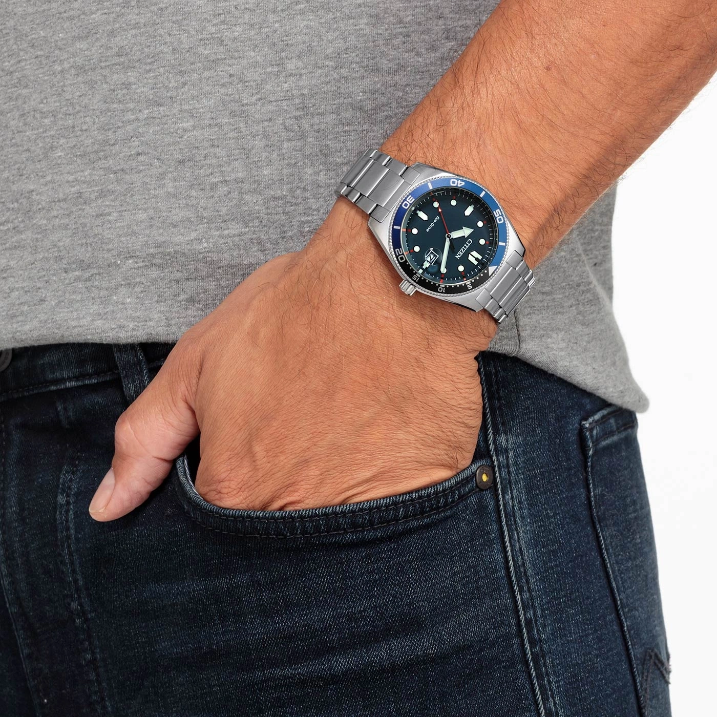 Mann mit Citizen-Uhr, Hand in der Tasche, blaue Jeans und graues Hemd.