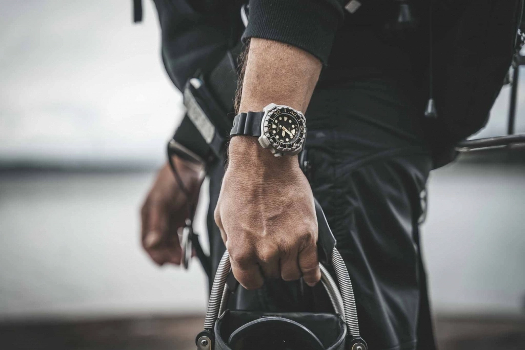Mann mit Uhr, hält Ausrüstung, Nahaufnahme, schwarzes Outfit, im Freien