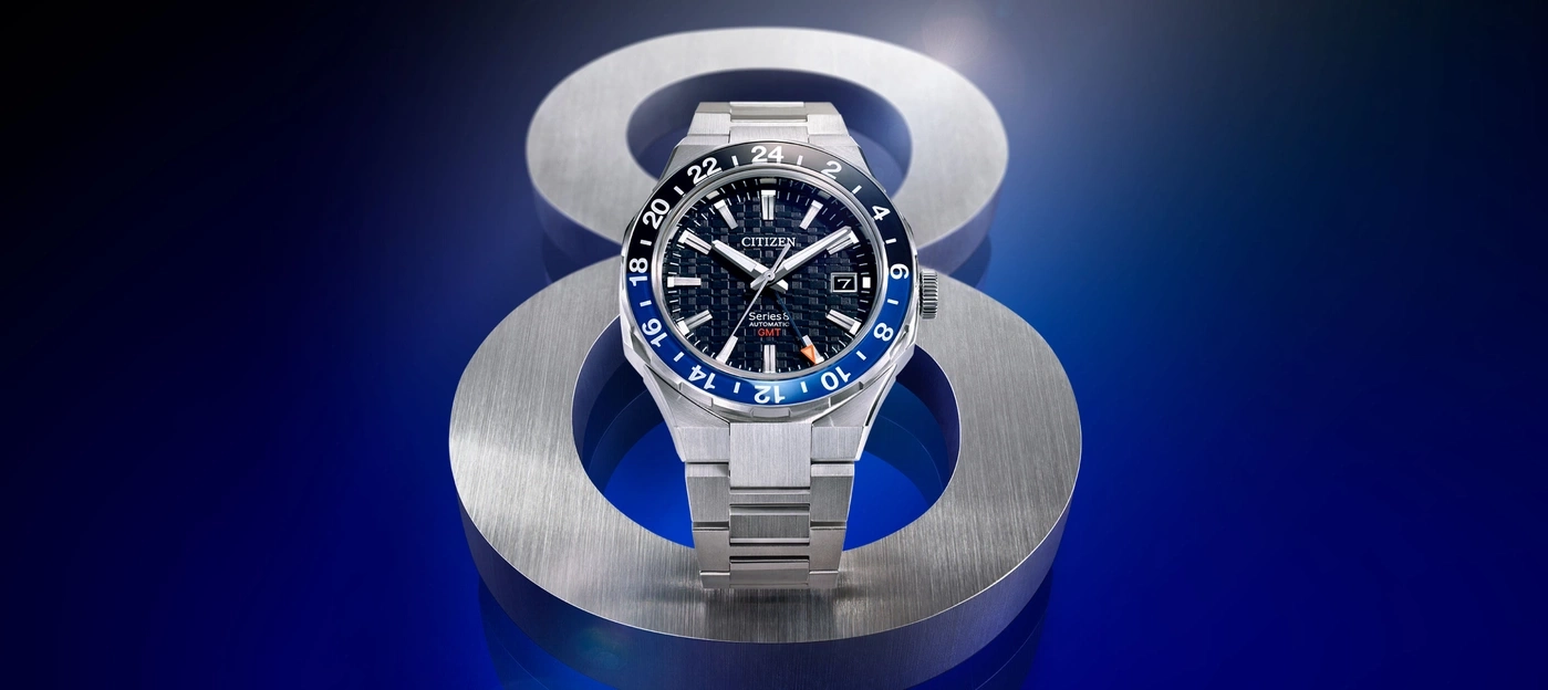 Citizen Series 8 Automatik GMT Uhr auf Metallständer, blauer Hintergrund.