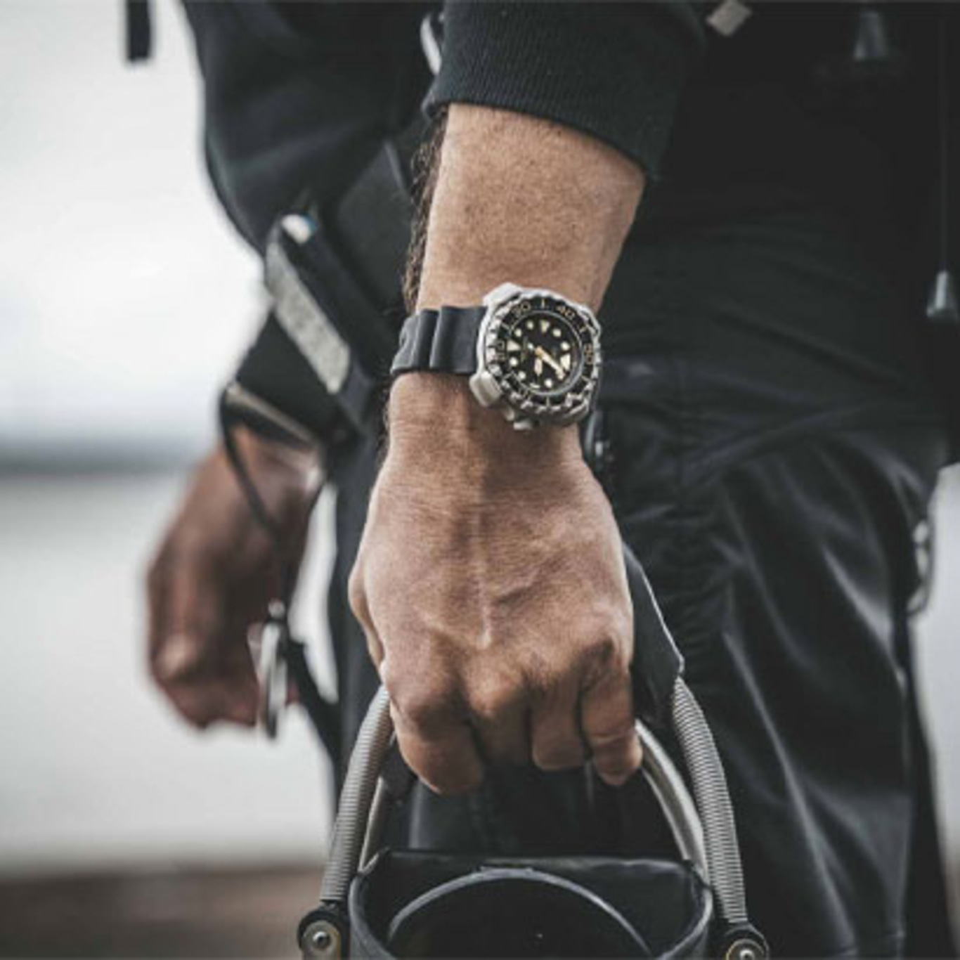 Mann mit Uhr, hält Ausrüstung, Nahaufnahme, schwarzes Outfit, Outdoor-Aktivität