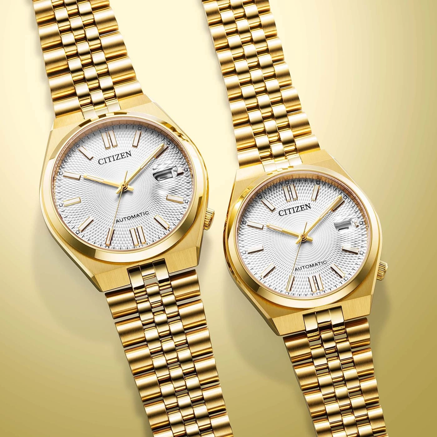Zwei goldene Citizen Automatikuhren mit weißen Zifferblättern auf goldenem Hintergrund.