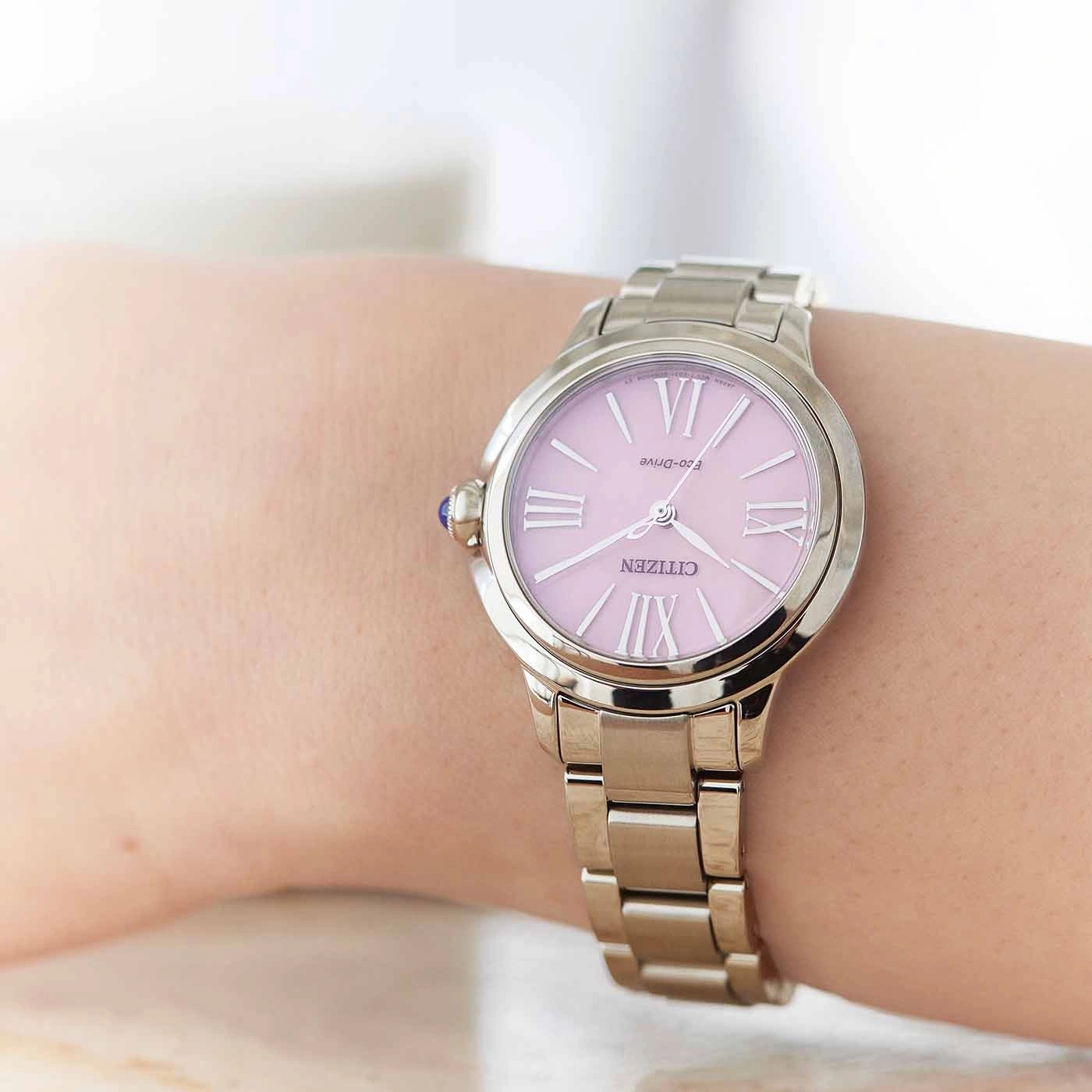 Nahaufnahme einer Citizen-Uhr am Handgelenk, rosa Zifferblatt, silbernes Armband.