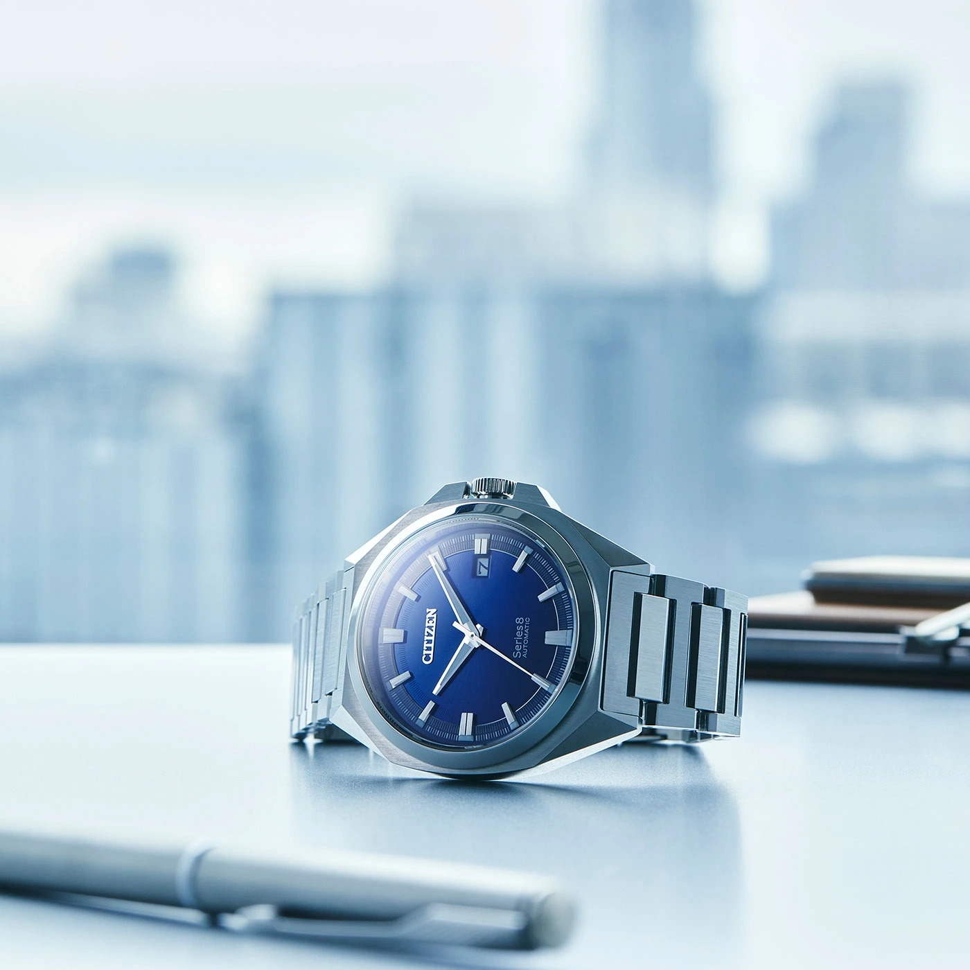 Citizen Series 8 Uhr mit blauem Zifferblatt auf einem Schreibtisch mit Stift.